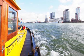 Rondvaartboot van de havendienst met passagiers vaart door de haven, gefotografeerd door Theo de Man in 2018 met het Maritiem Museum Rotterdam op de achtergrond.
