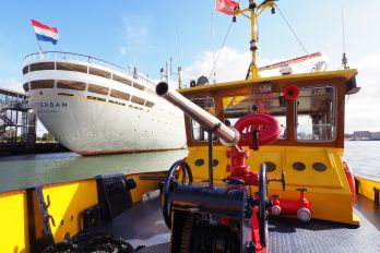 Rondvaartboot van de havendienst vaart door de haven met passagiers, op de achtergrond het Maritiem Museum Rotterdam, gefotografeerd door Theo de Man.