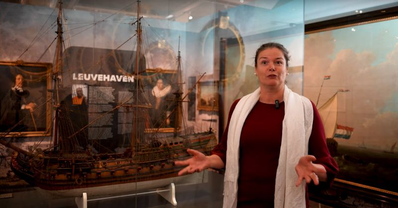 Portretfoto van Annette de Wit staand bij opgezette scheepsbouwpresentatie in de tentoonstelling Opgedoken in het Maritiem Museum Rotterdam.