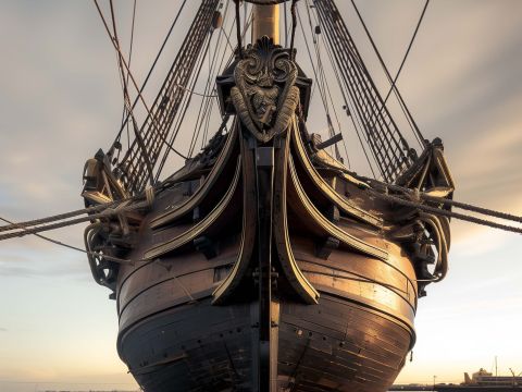 Zwart-witfoto van een historisch vrachtschip dat door het water vaart, met een rookpluim uit de schoorsteen en bemanning zichtbaar aan dek. De afbeelding toont de maritieme sfeer van een vervlogen tijdperk.