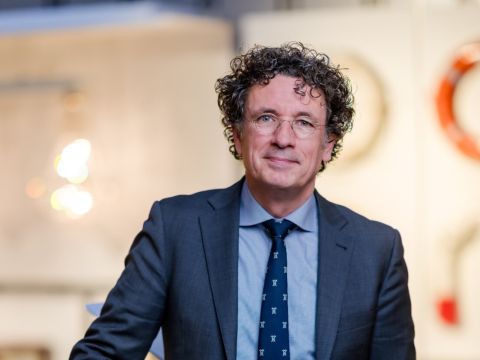 Portret van directeur Bert Boer in het Maritiem Museum Rotterdam, staand in een tentoonstellingsruimte met nautische voorwerpen op de achtergrond.