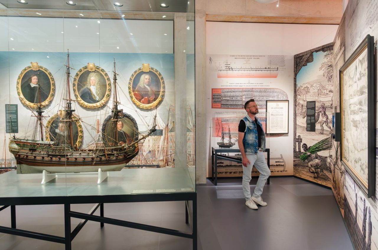 Bezoekers bekijken interactieve borden en kaartmateriaal in de tentoonstelling Bestemming Havenstad in het Maritiem Museum Rotterdam, met focus op havenontwikkeling.