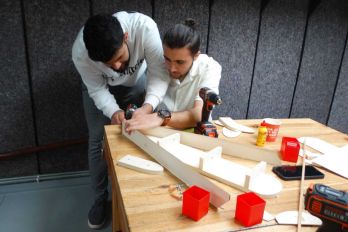 Studenten werken geconcentreerd aan technische opdrachten tijdens een educatief programma in het Maritiem Museum Rotterdam, omringd door gereedschap en meetapparatuur.