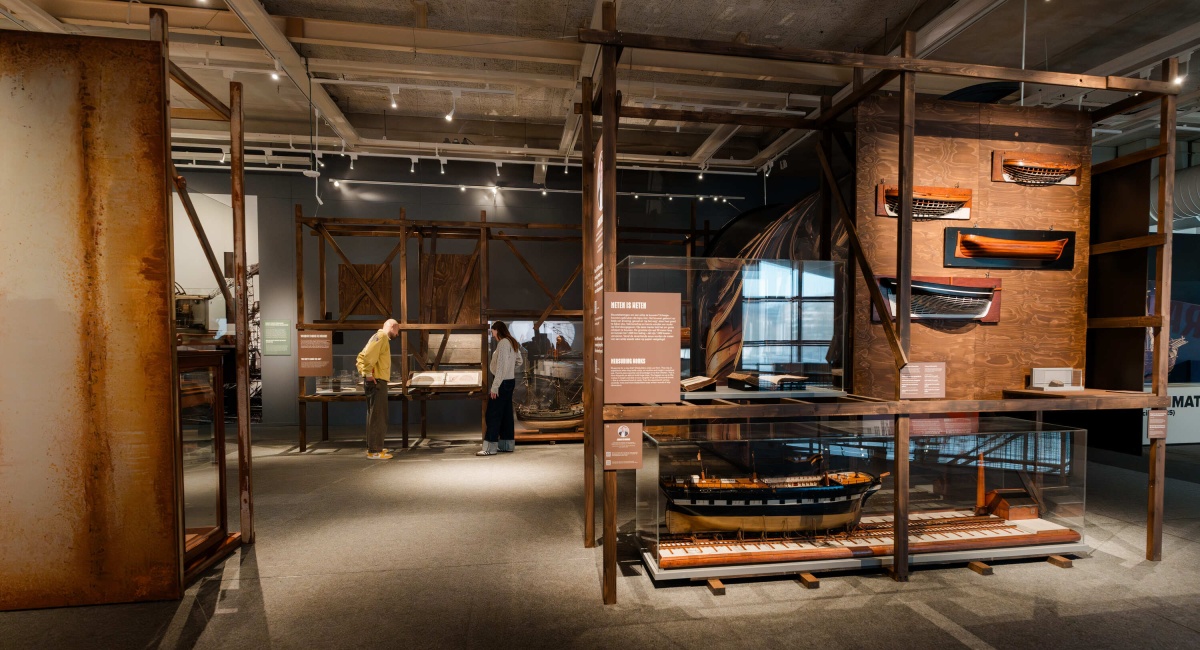 Brede opname van bezoekers in de centrale hal van de tentoonstelling Te Water, met reflecterend wateroppervlak en tentoonstellingspanelen.