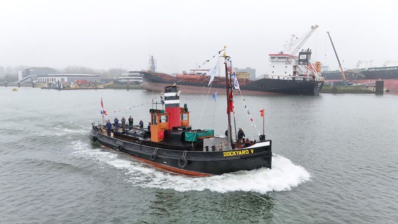 Grote historische zeesleper met tekst Dockyard V ligt afgemeerd in de museumhaven van het Maritiem Museum Rotterdam, met bezoekers aan wal.
